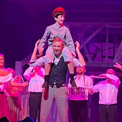 A man is carrying a child on his shoulders on a stage