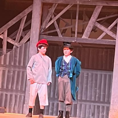 Two young boys are standing next to each other on a stage.