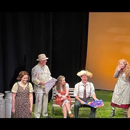 A group of people are sitting on a bench on a stage.