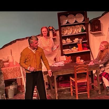 A group of people are standing around a table on a stage.