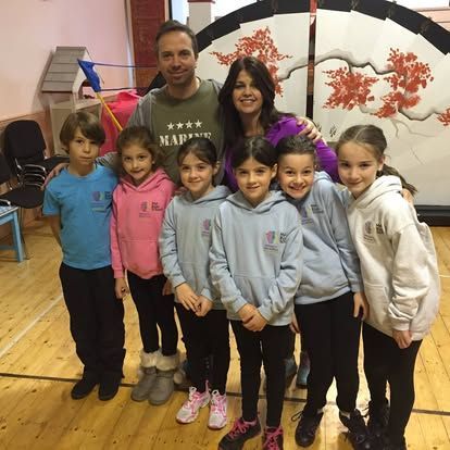 A group of children posing for a picture with a man in a military shirt