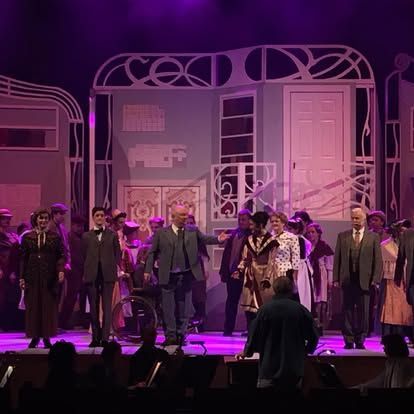 A group of people are standing on a stage with purple lights.