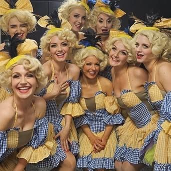 A group of women dressed in yellow and blue dresses are posing for a picture.