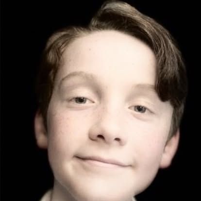 A close up of a young boy 's face with a black background.
