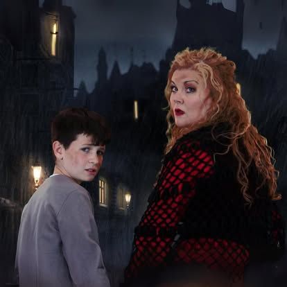 A woman and a boy are standing next to each other in front of a castle.