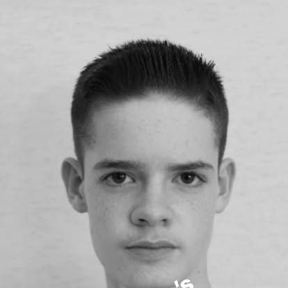 A young boy with short hair is looking at the camera in a black and white photo.