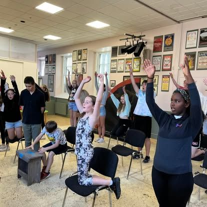A group of people are standing in a room with their arms in the air.