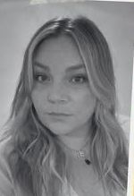 A black and white photo of a smiling woman wearing a white shirt.