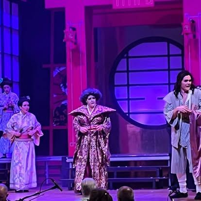 A group of people are standing on a stage in front of a microphone.