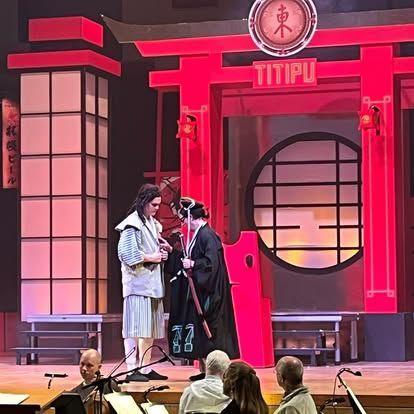 A group of people standing on a stage in front of a sign that says titipu