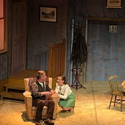 A man is sitting in a chair talking to a woman on a stage.