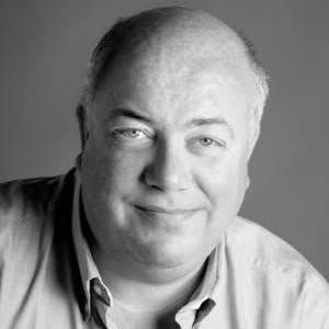 A bald man is smiling in a black and white photo.