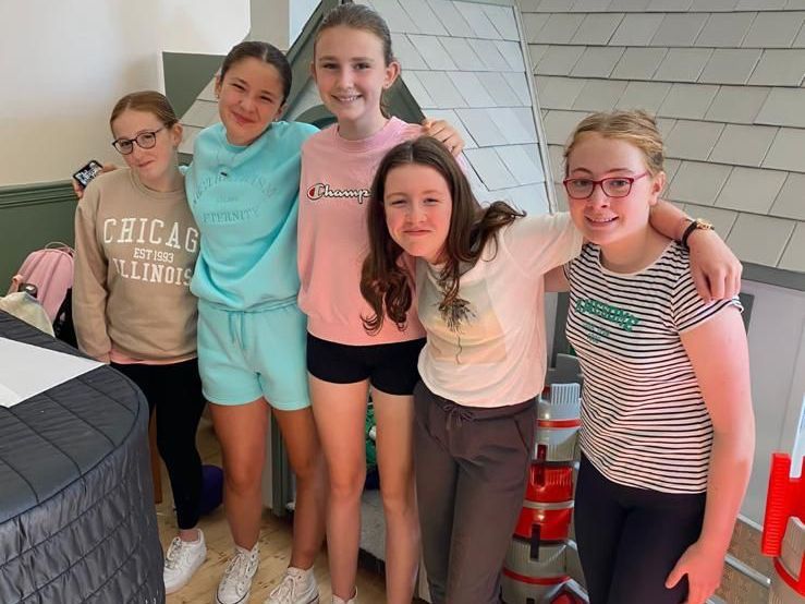 A large group of people are dancing on a stage in front of a conductor.