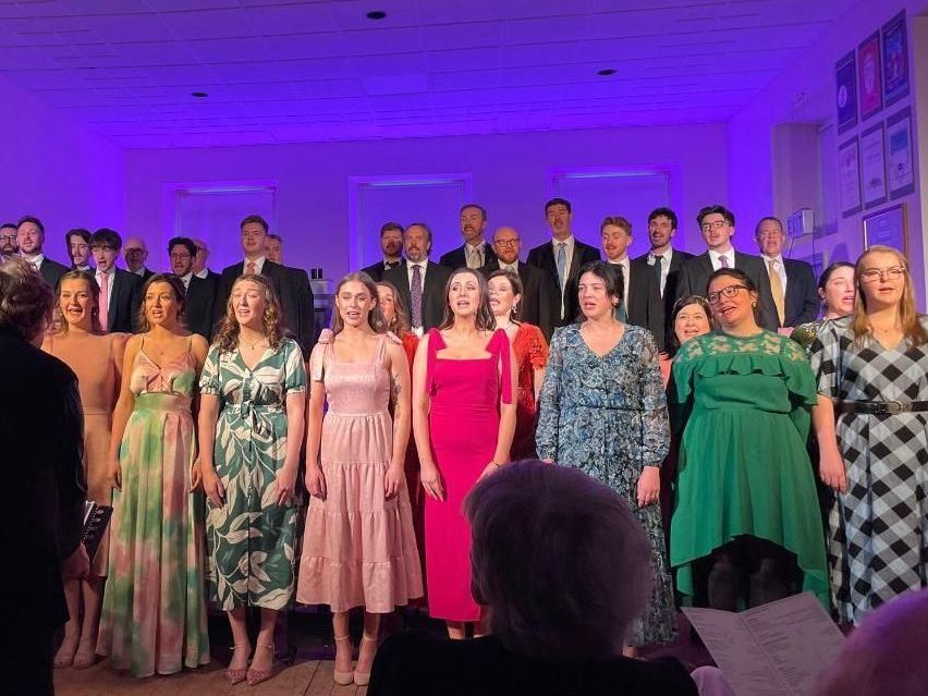 A large group of people are singing together in a room.
