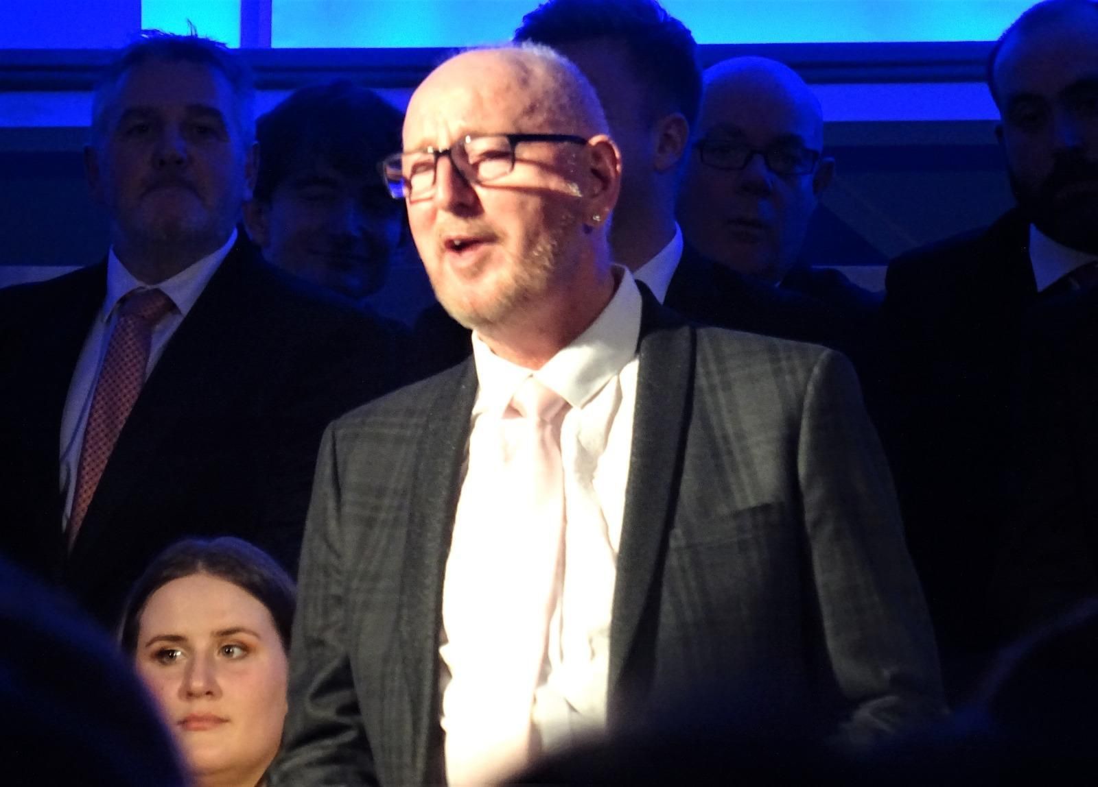 A man in a suit and tie is standing in front of a crowd.