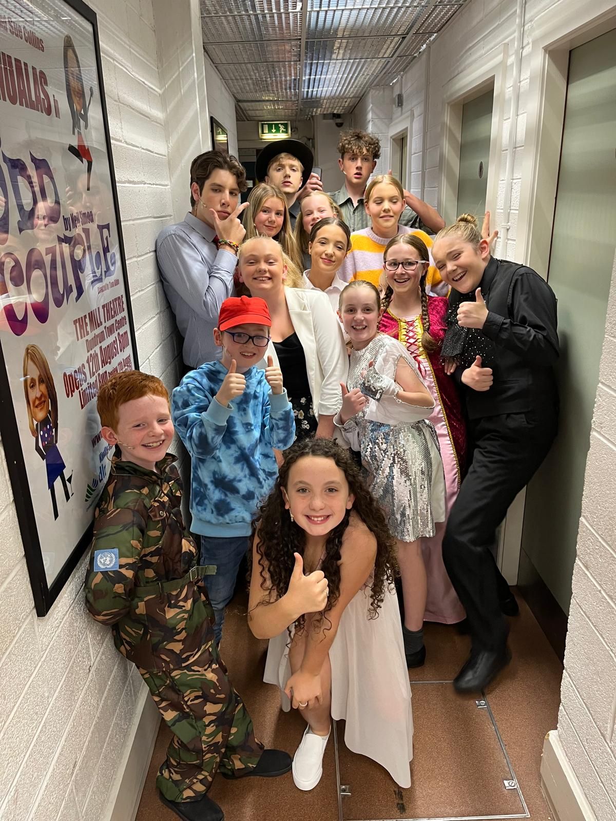 A group of cowboys are standing in front of a wooden building on a stage.