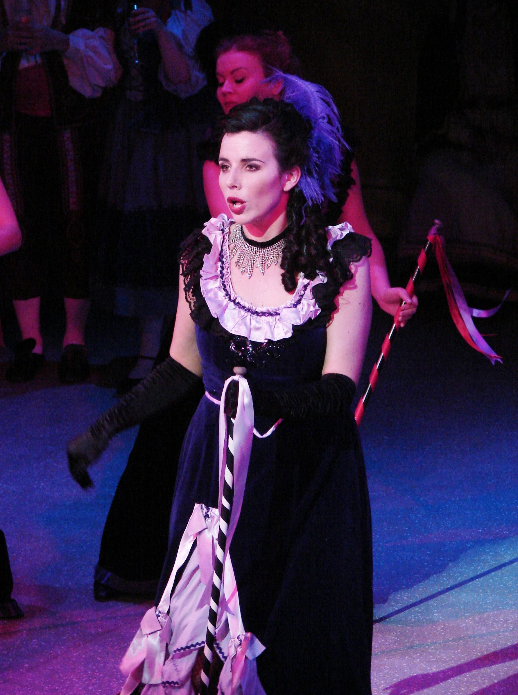 A woman in a black dress is singing on a stage