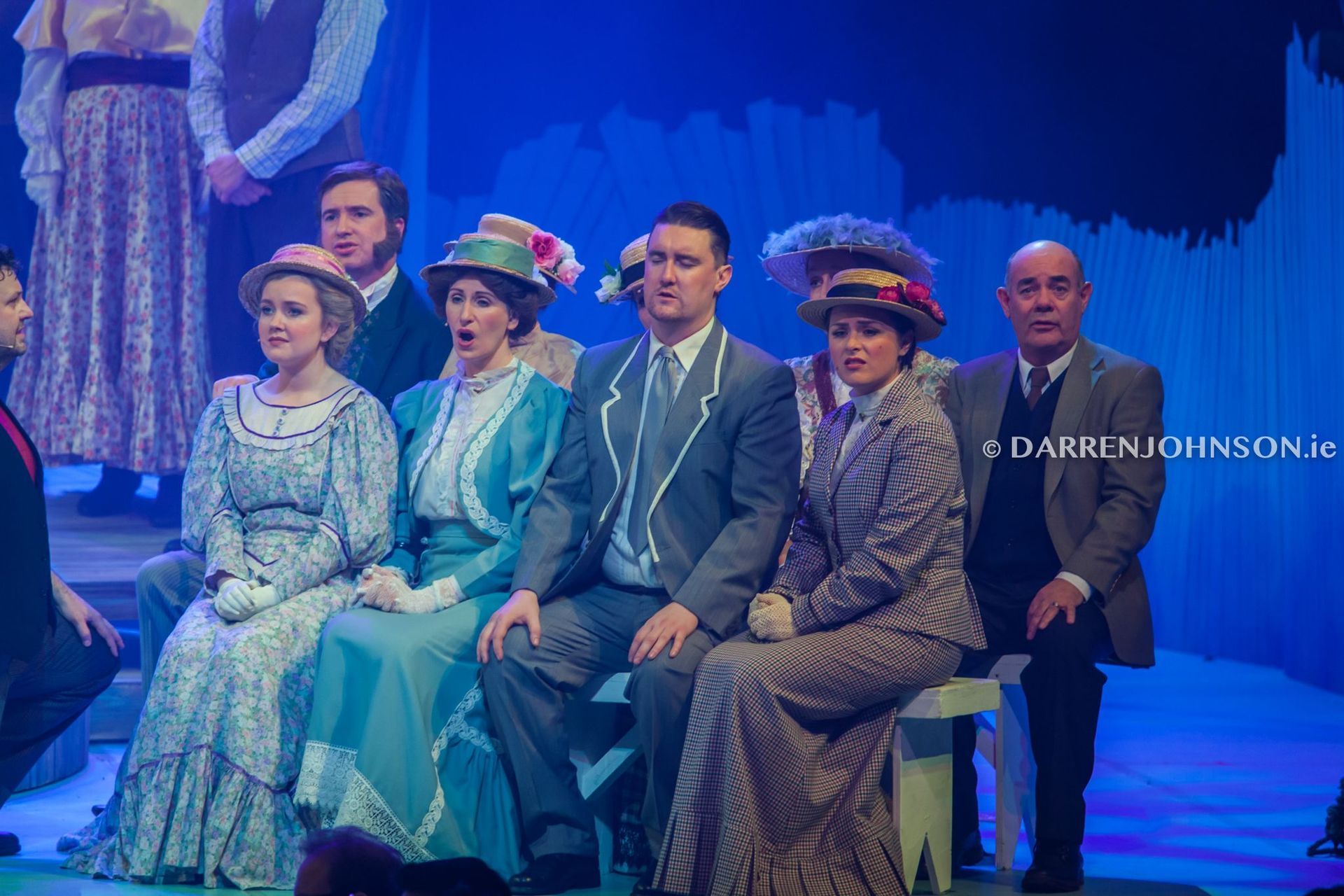 A group of people are sitting on a bench on a stage.