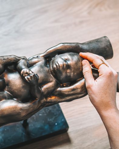 Een persoon houdt een beeldje van een baby in zijn handen.