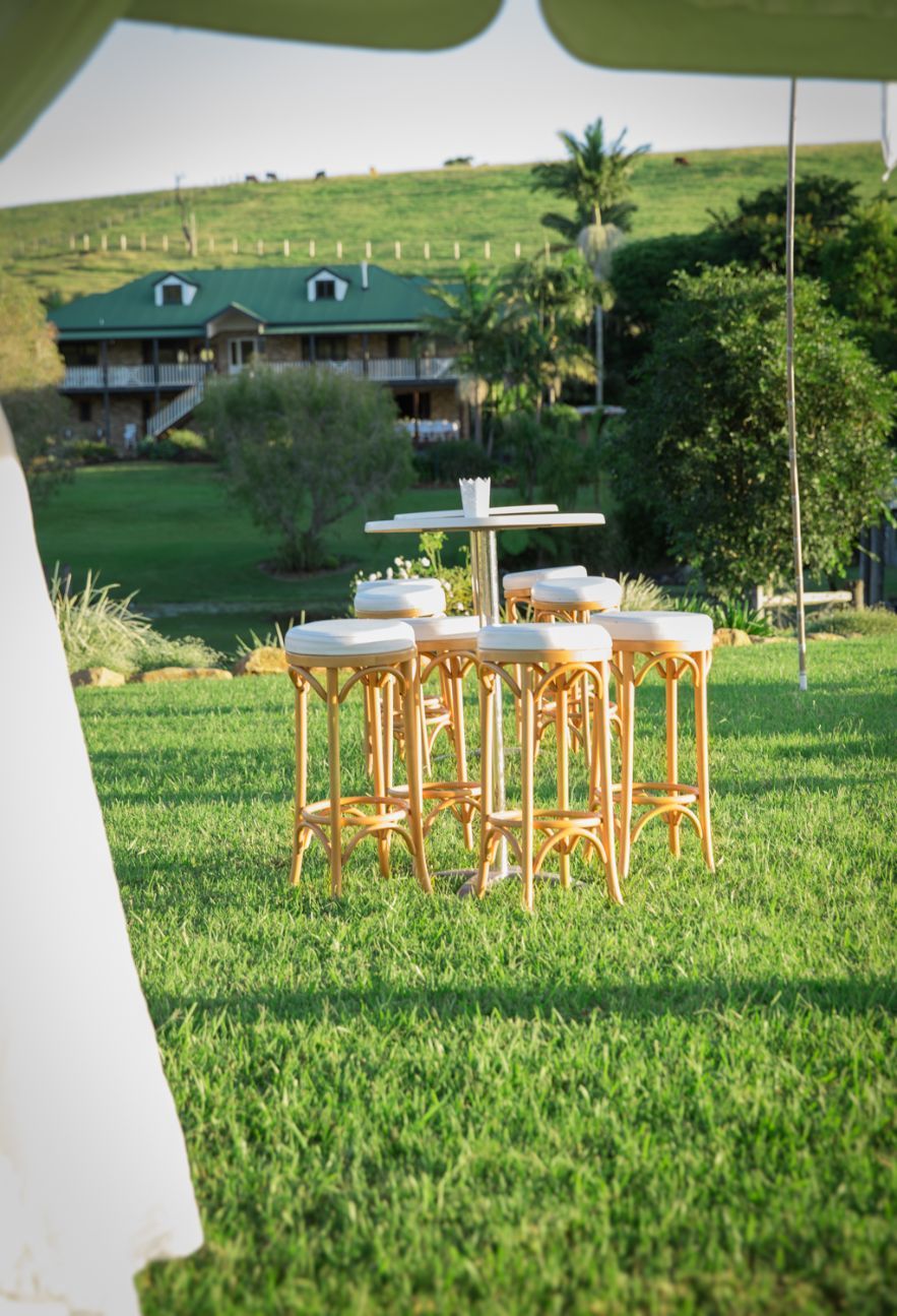 White Wooden Bar Stools And Tables On A Green Grass — Wedding & Event Hire In Goonellabah, NSW