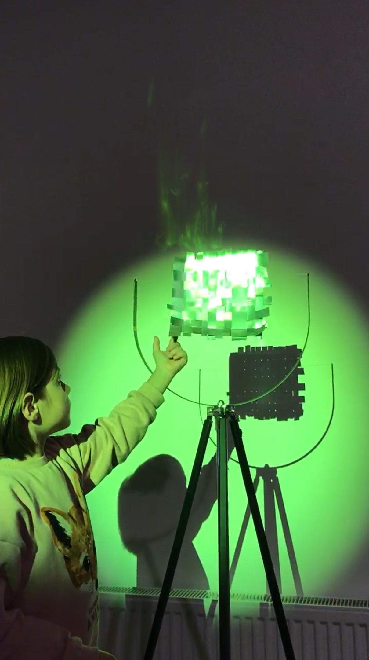 Little girl playing with reflective, metal woven artwork