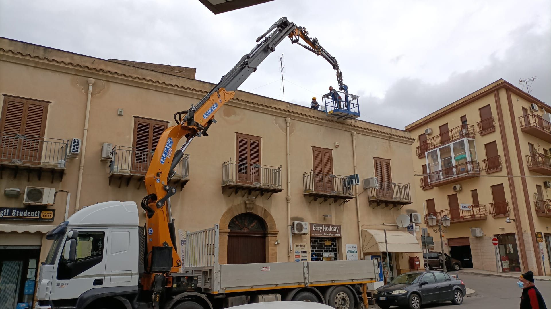 Una gru solleva una piattaforma sul tetto