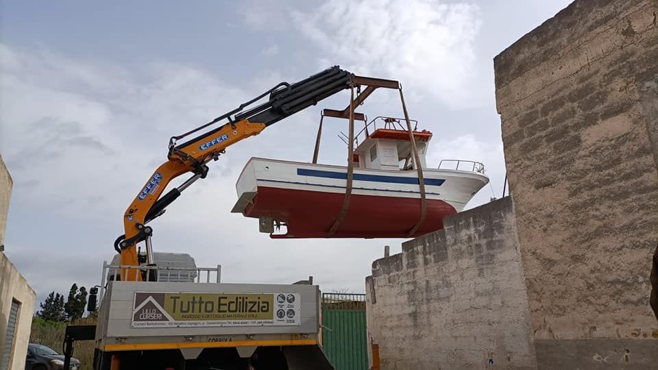 Una gru solleva una barca rossa