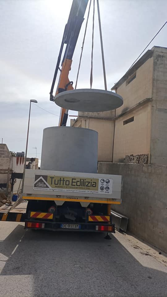 Una gru solleva un coperchio di cemento