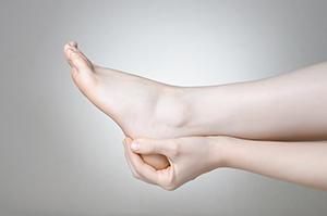 A woman is holding her foot in pain.