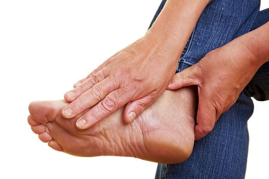 A person is holding their foot in pain.