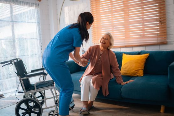 A nurse is shaking hands with an elderly woman in a wheelchair.