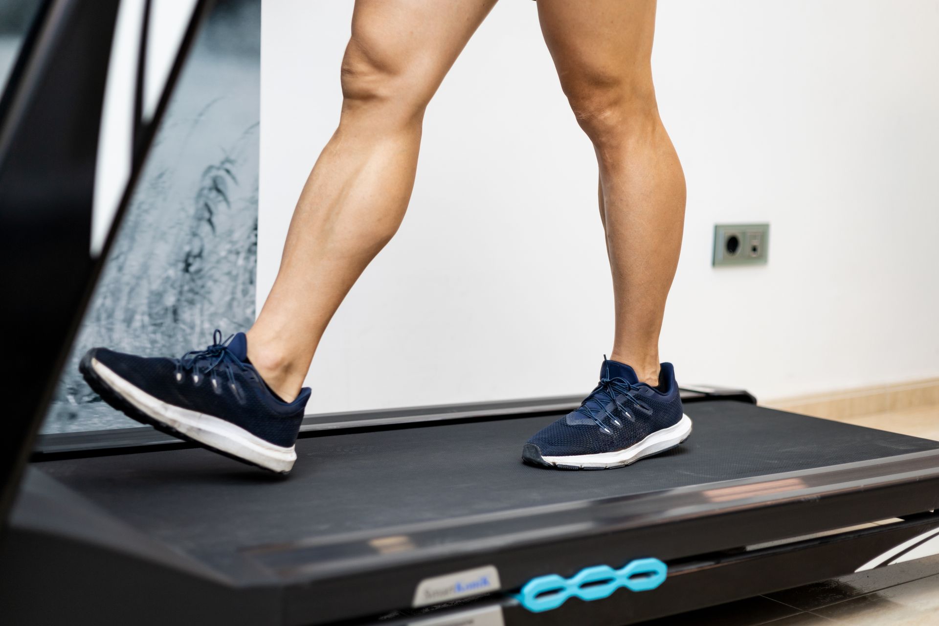 A person is walking on a treadmill wearing blue shoes.