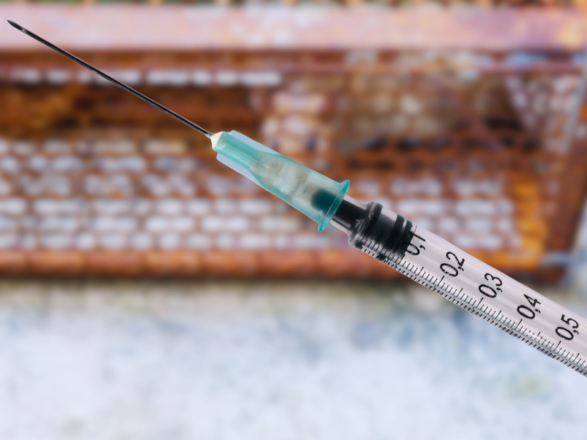 A syringe is sitting on a table next to a keyboard.