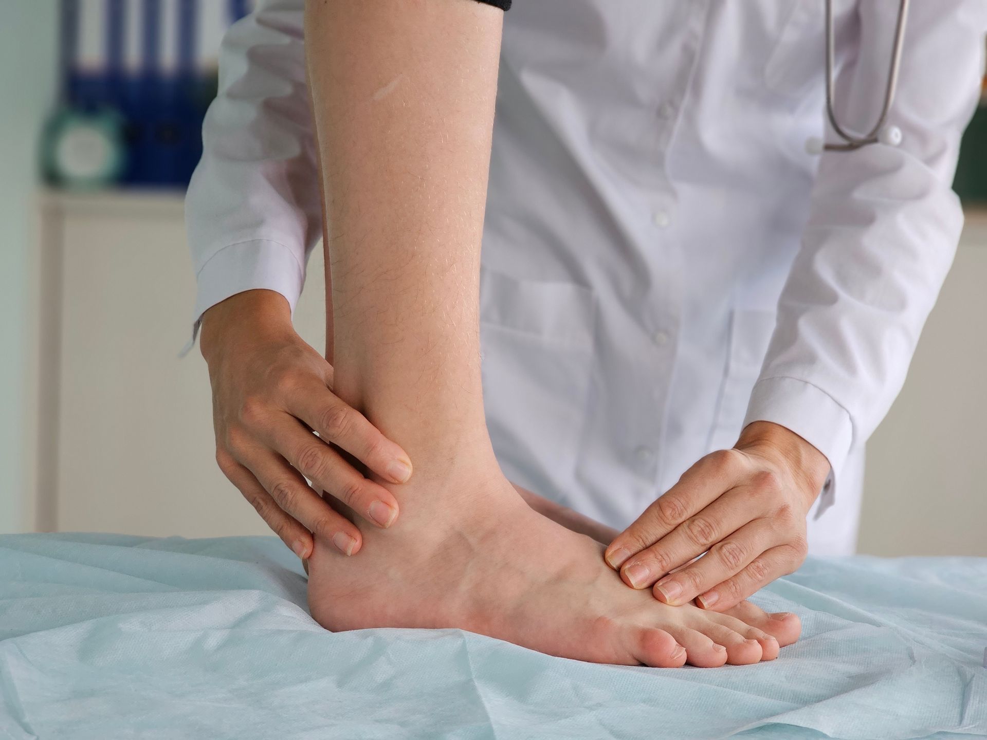 A doctor is examining a patient 's foot on a bed.
