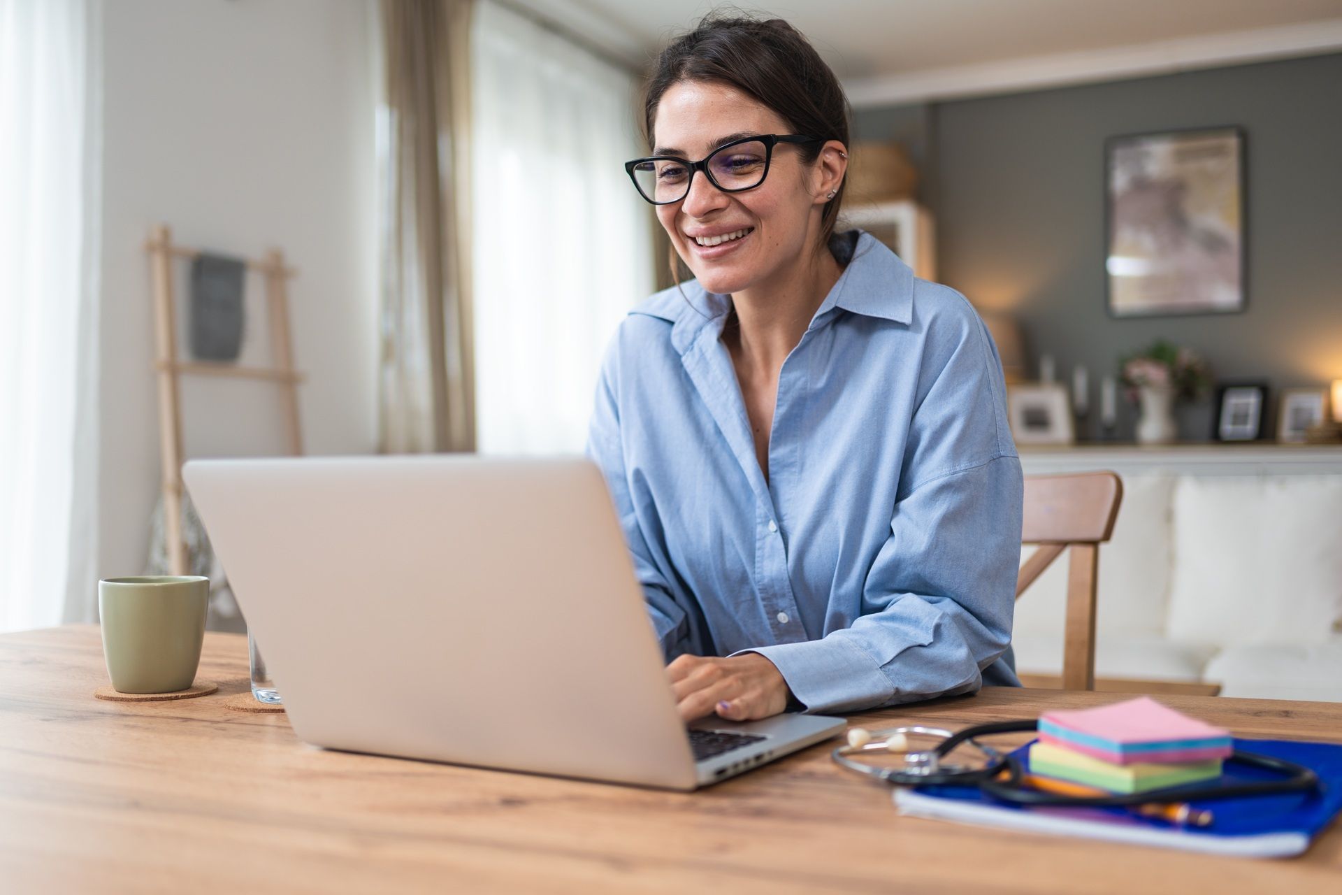 A woman is sitting at a table using a laptop computer.