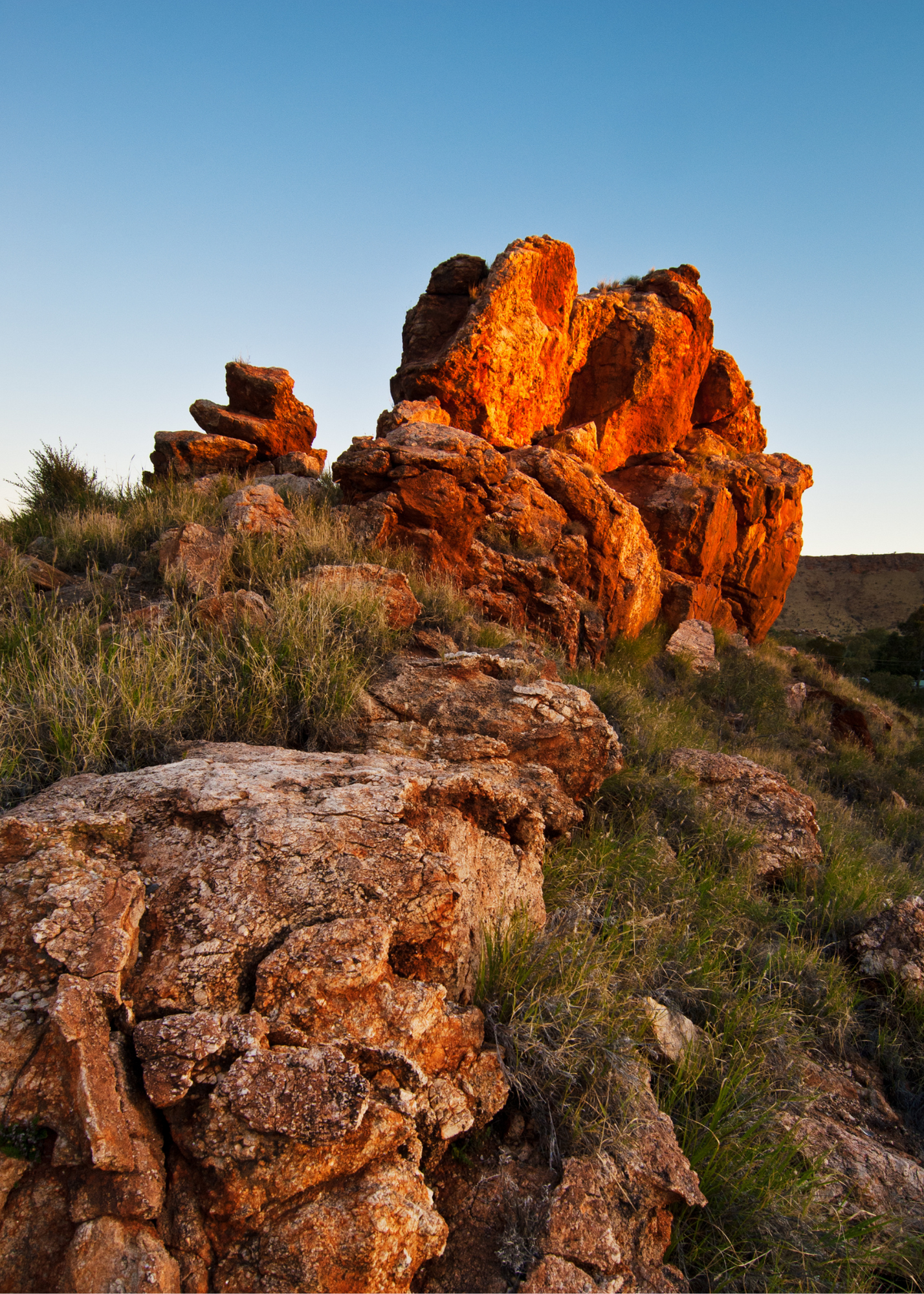 A large rock formation is sitting on top of a hill.