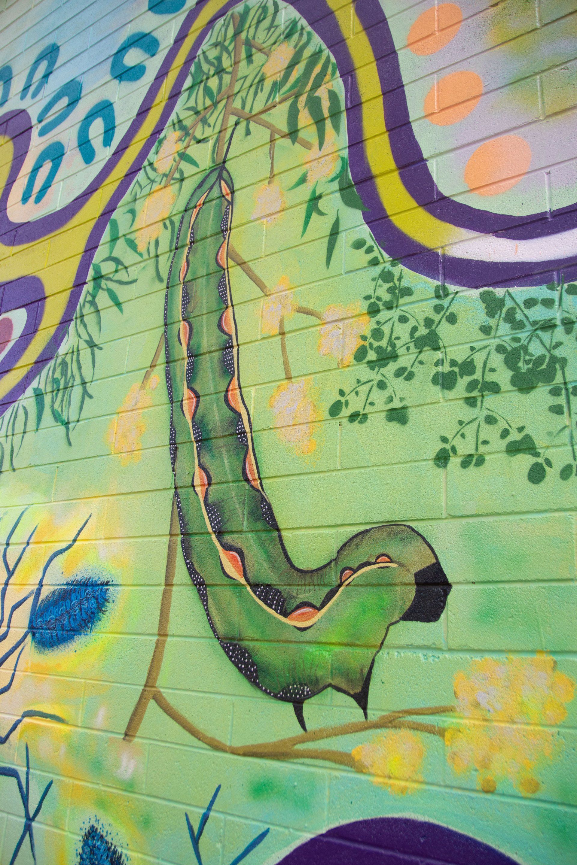 A green caterpillar is painted on a brick wall.