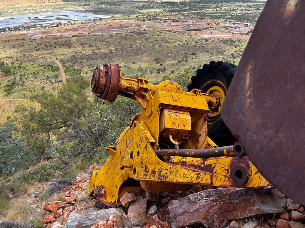 A yellow tractor is sitting on top of a rocky hill.