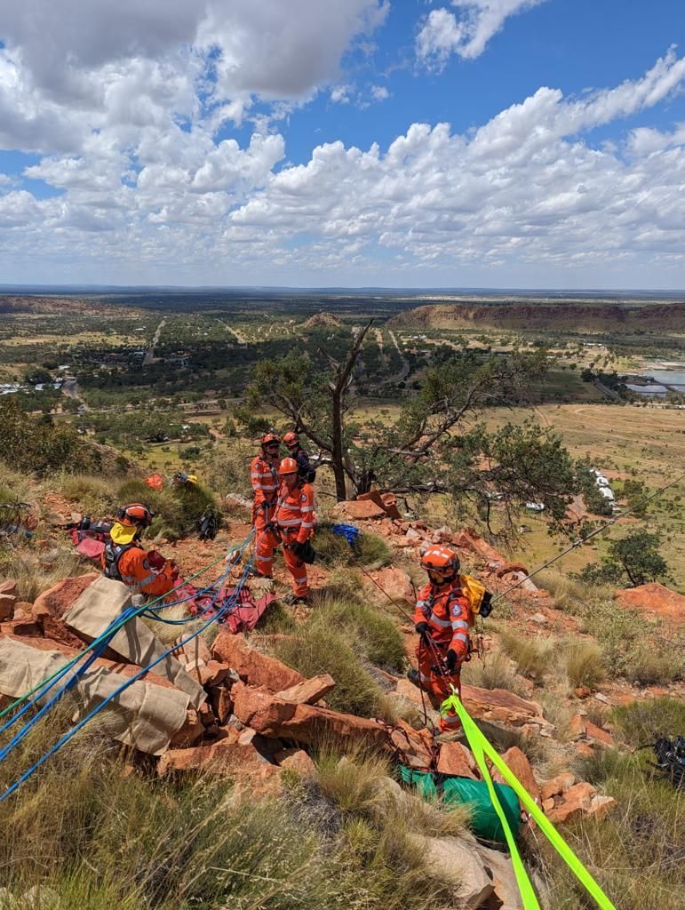 A group of people are standing on top of a rocky hill.