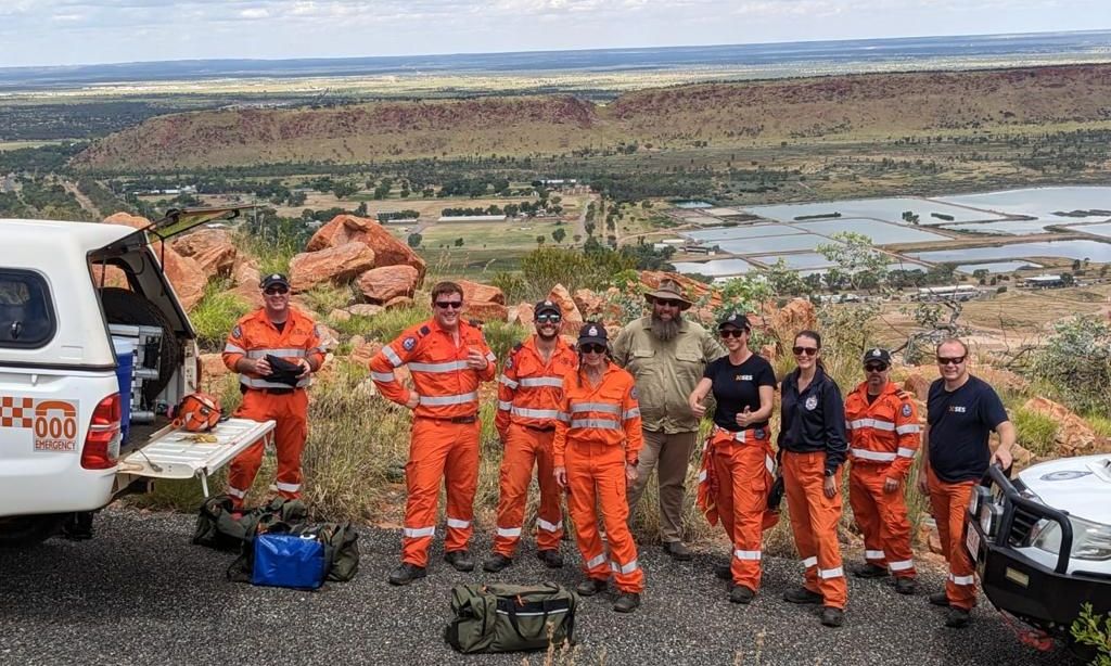 A group of people in orange jumpsuits are standing in front of a truck.