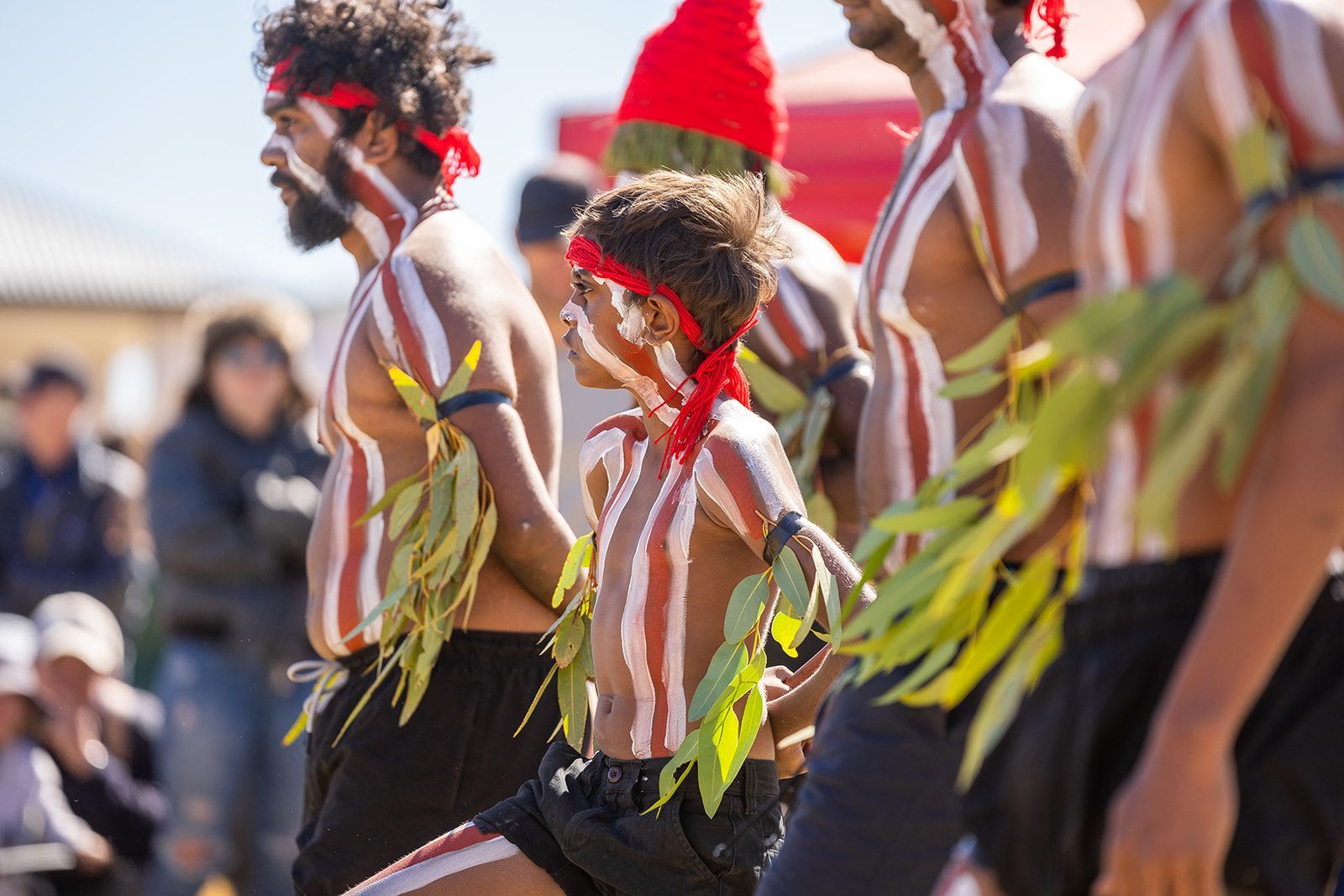 A group of men and a boy are dancing in front of a crowd.