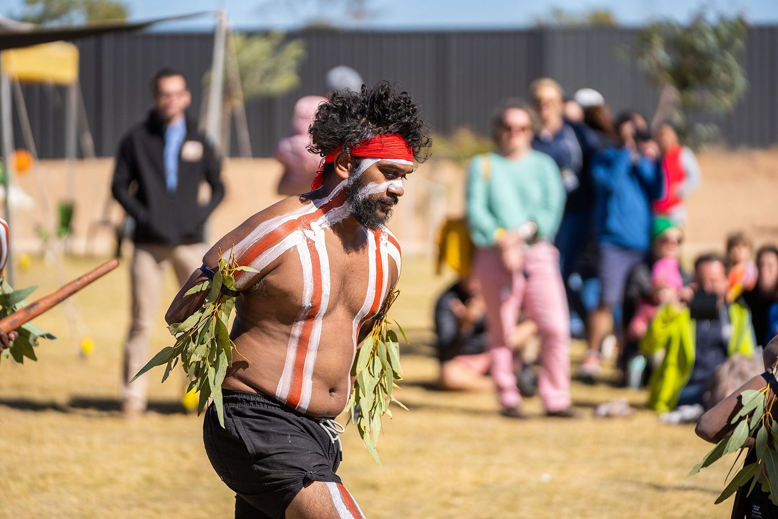 A man is dancing in front of a crowd of people in a field.