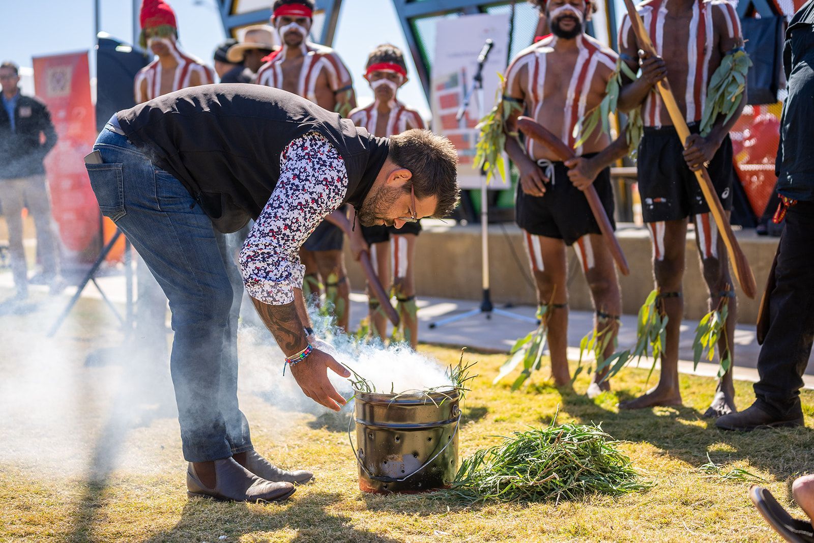 A man is kneeling down in front of a group of aboriginal men.