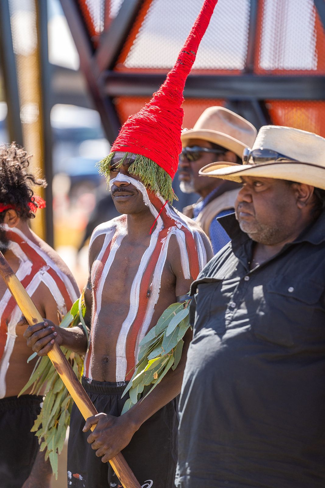 A group of men are standing next to each other wearing cowboy hats and holding sticks.