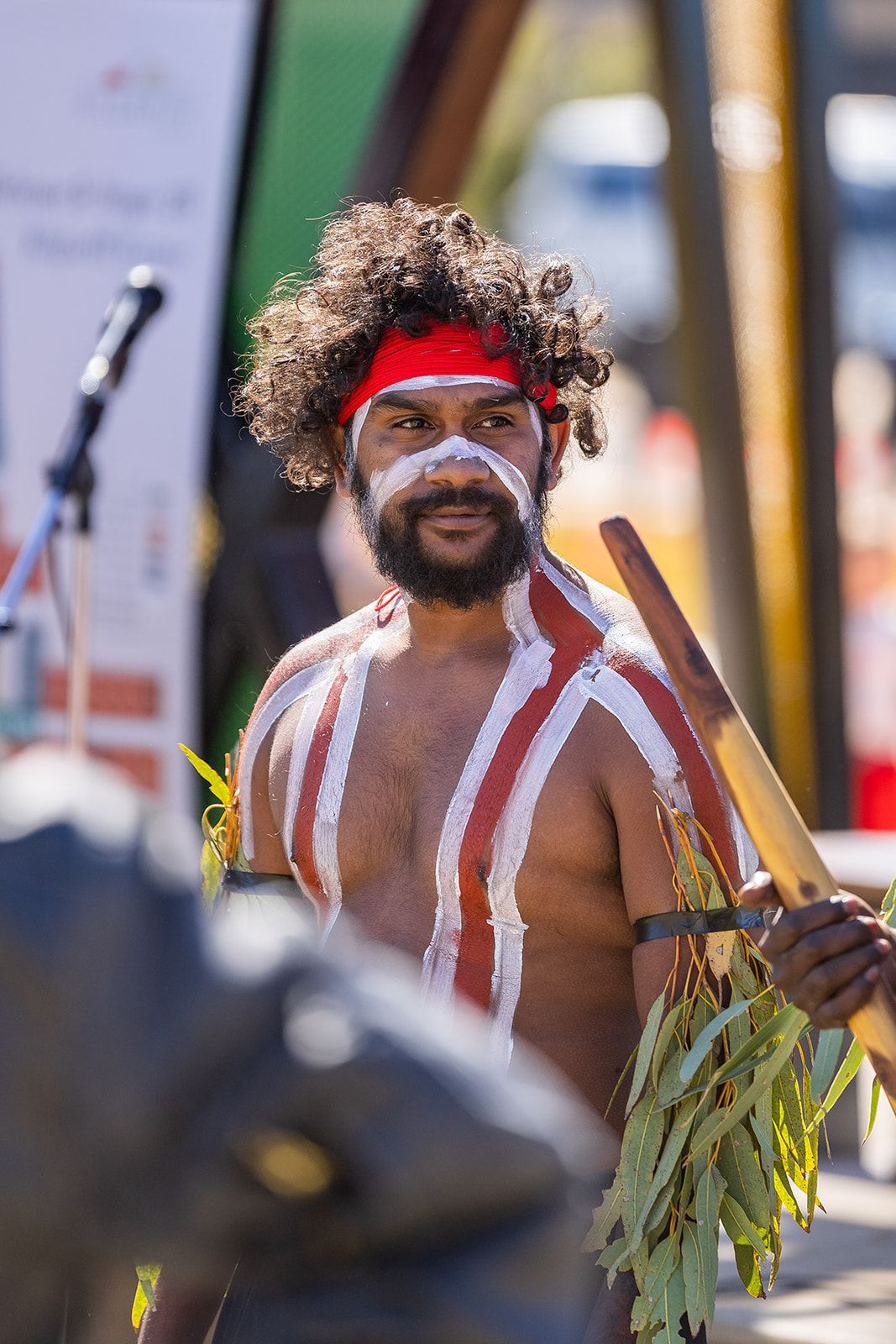 A man with a beard is wearing a red and white costume and holding a stick.