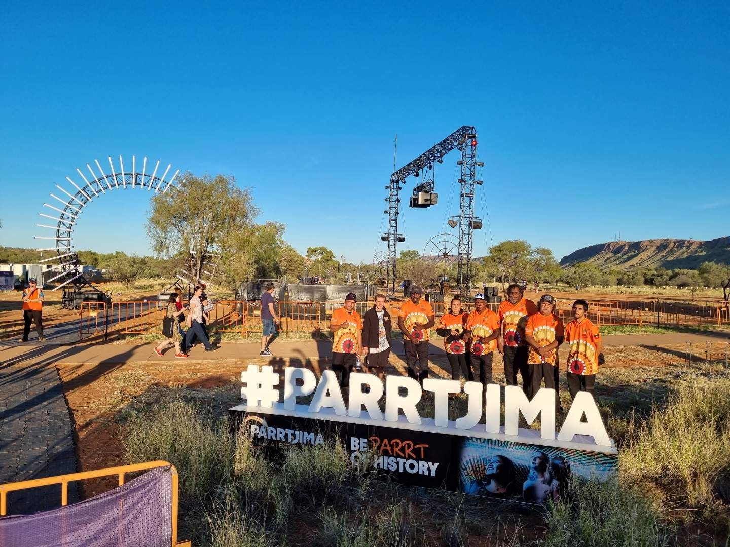 A group of people are standing in front of a sign that says parrtija.