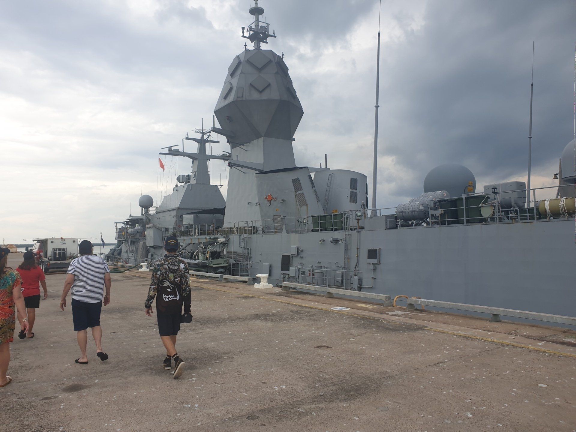 A group of people walking in front of a large ship