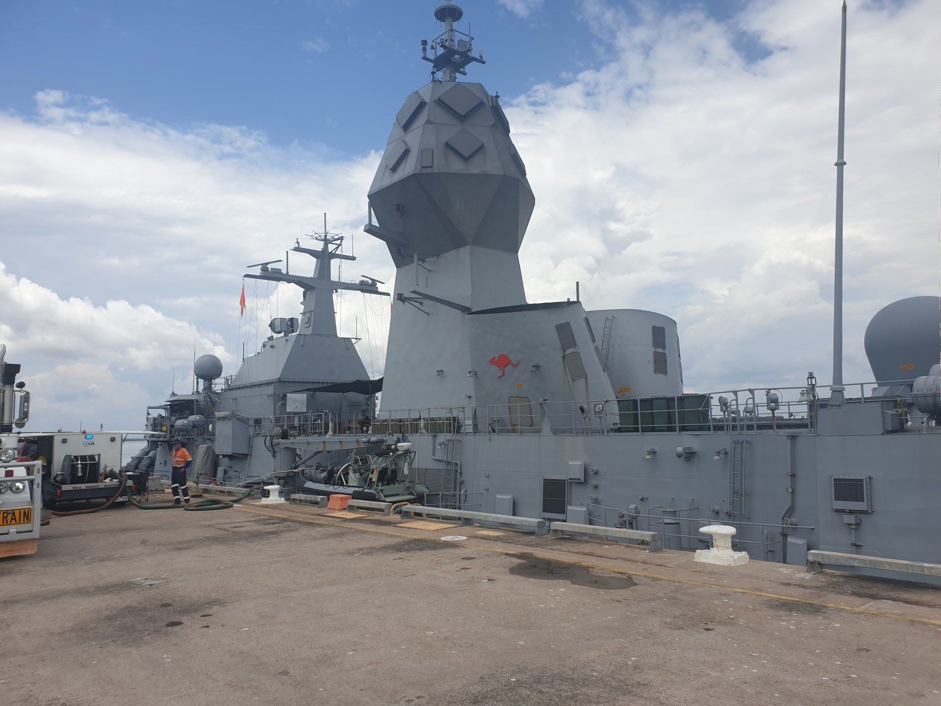 A large military ship is docked on a sunny day