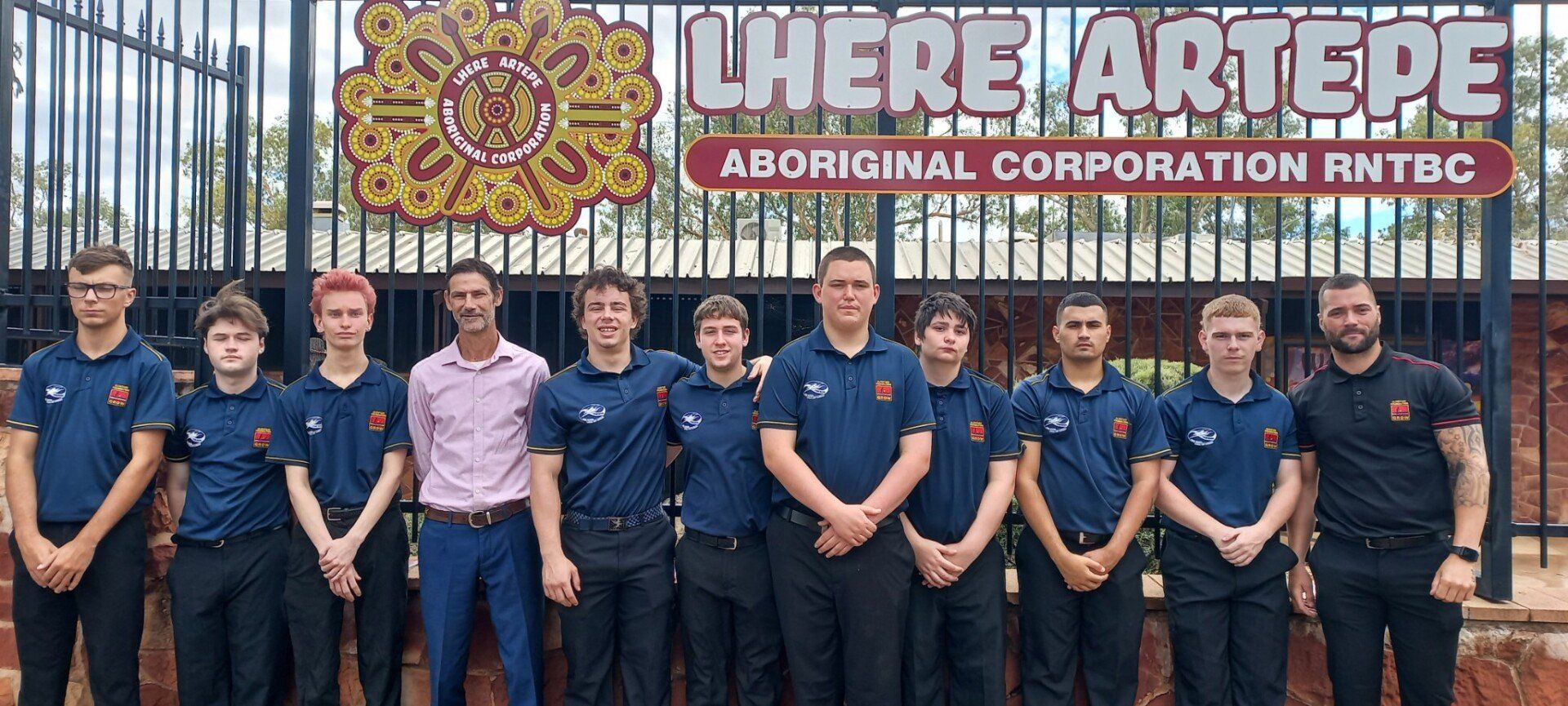 A group of young men are posing for a picture in front of a sign.