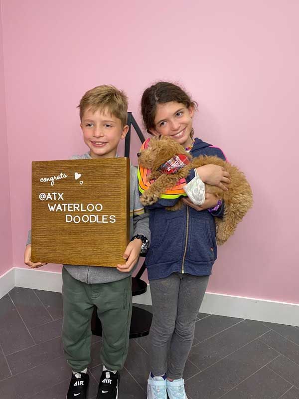 A boy and a girl are holding a puppy and a sign.